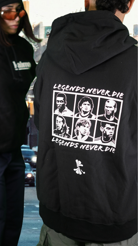 Person wearing a black hoodie with 'Legends Never Die' design on the back, standing on a New York City street.